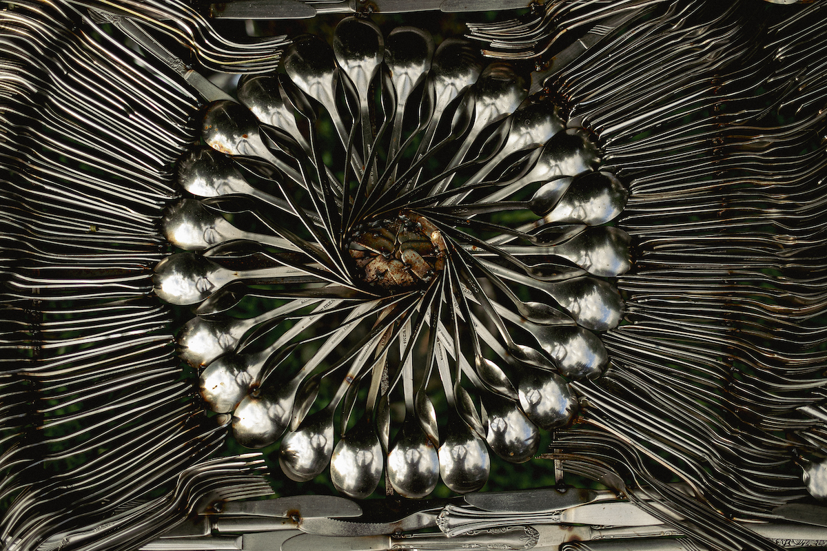 photo of table made out of cutlery, showcasing central decorative circle of welded spoons