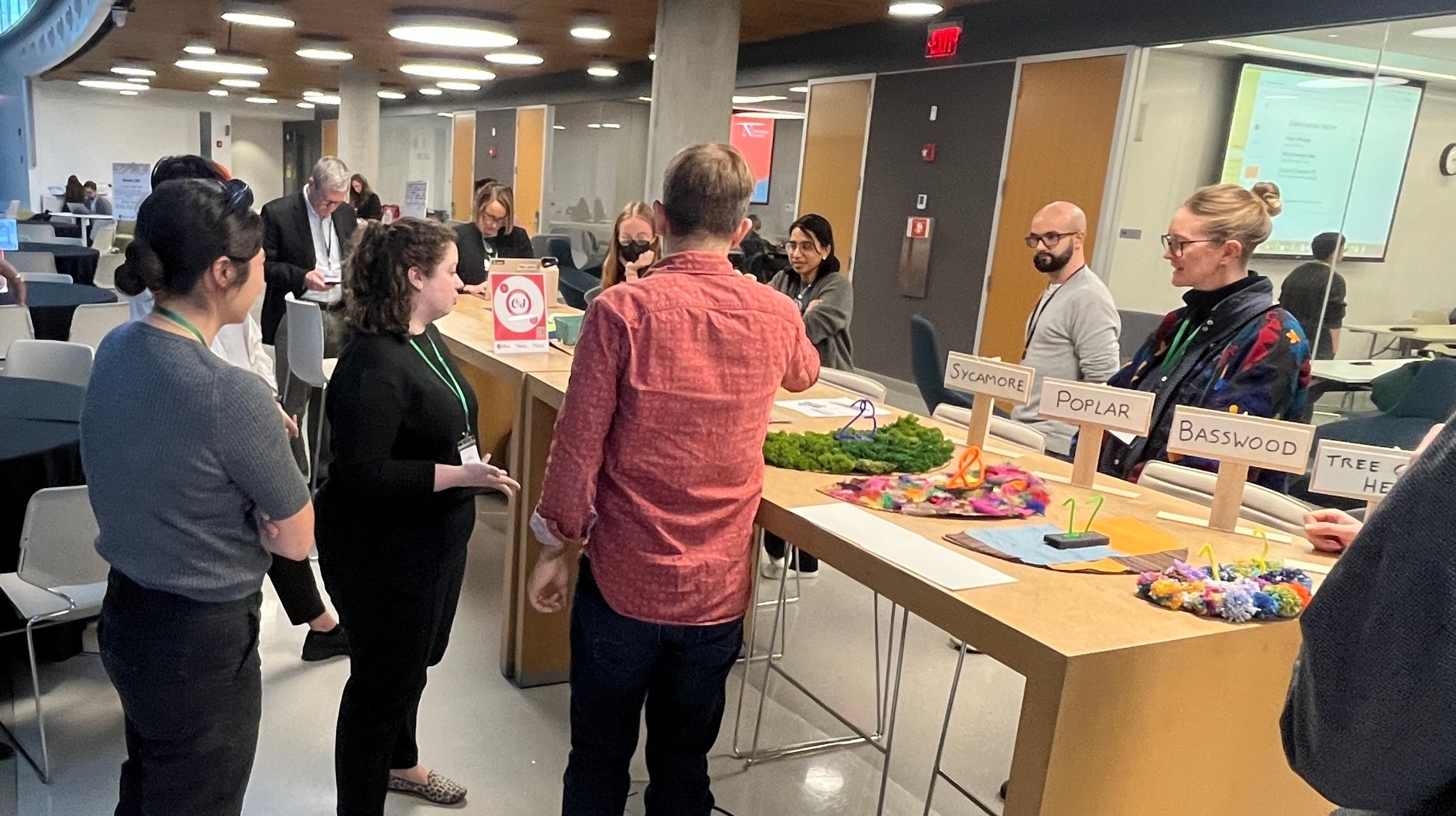 People standing around a tall table with data scultpures created out of craft materials on top of it.