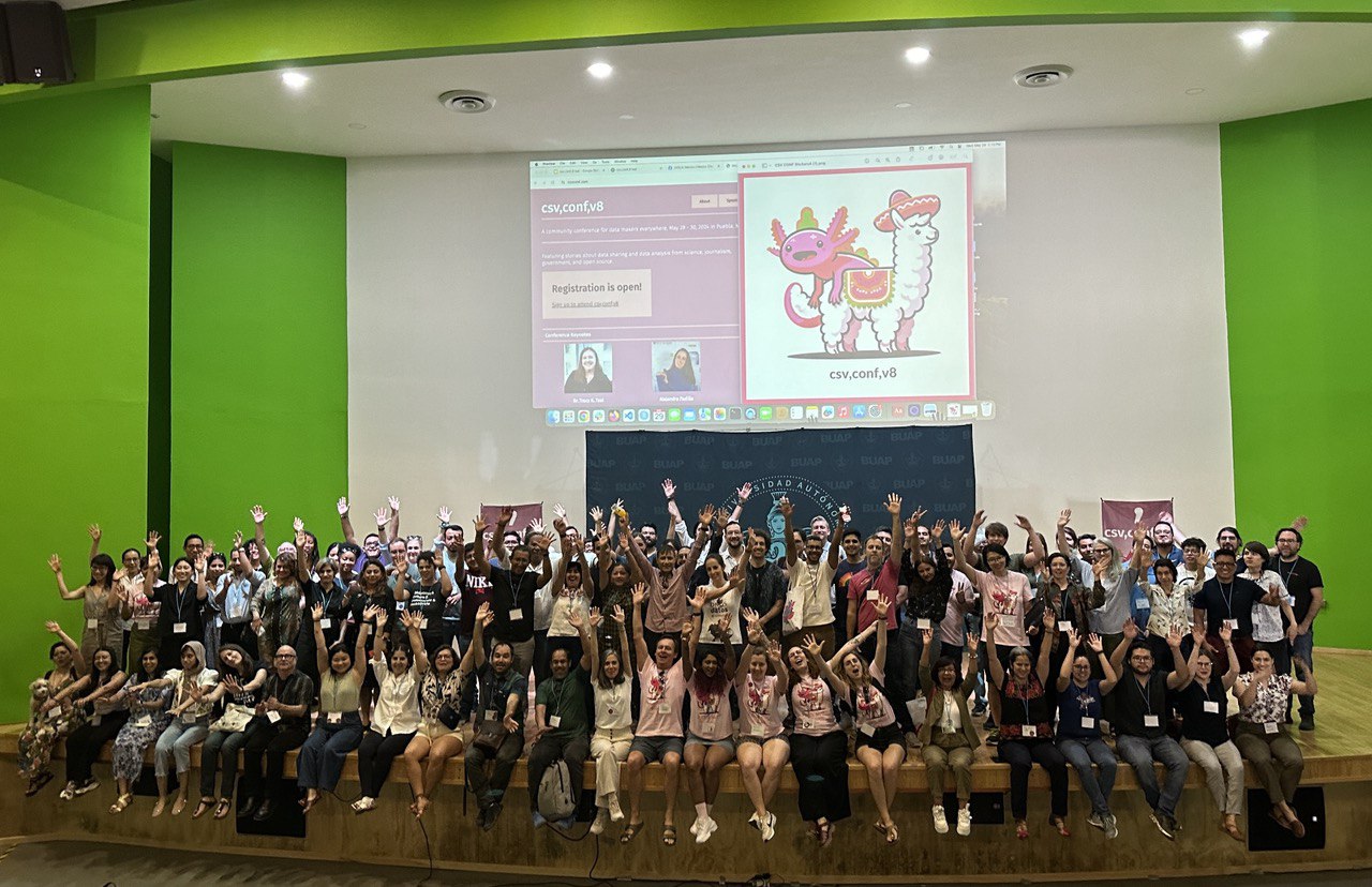 large group of event attendees on stage in front of slide with logos