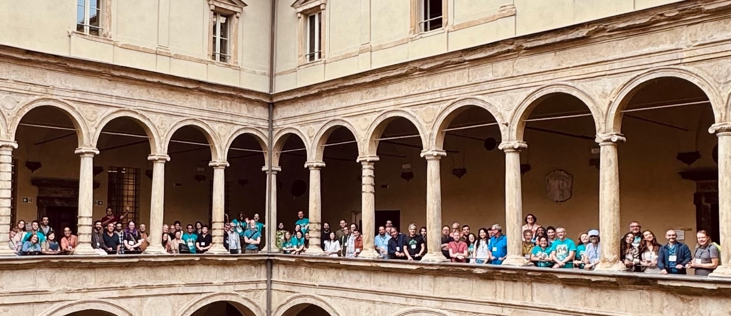 photo of 2nd floor of building showing lots of people standing within arches