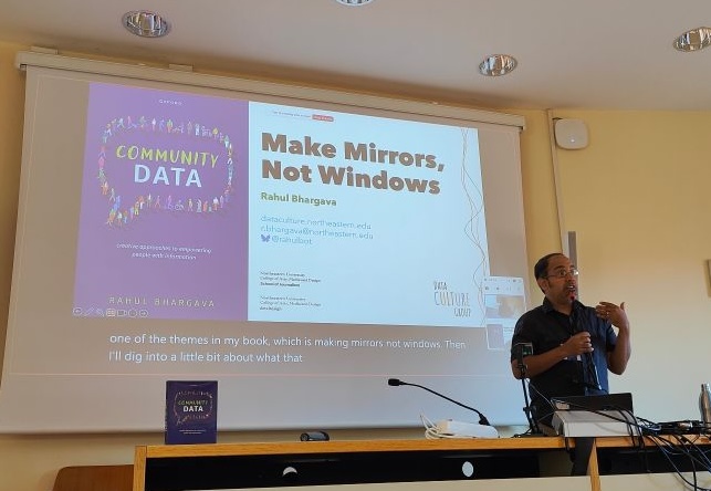 photo of me speaking with a slide about my book behind