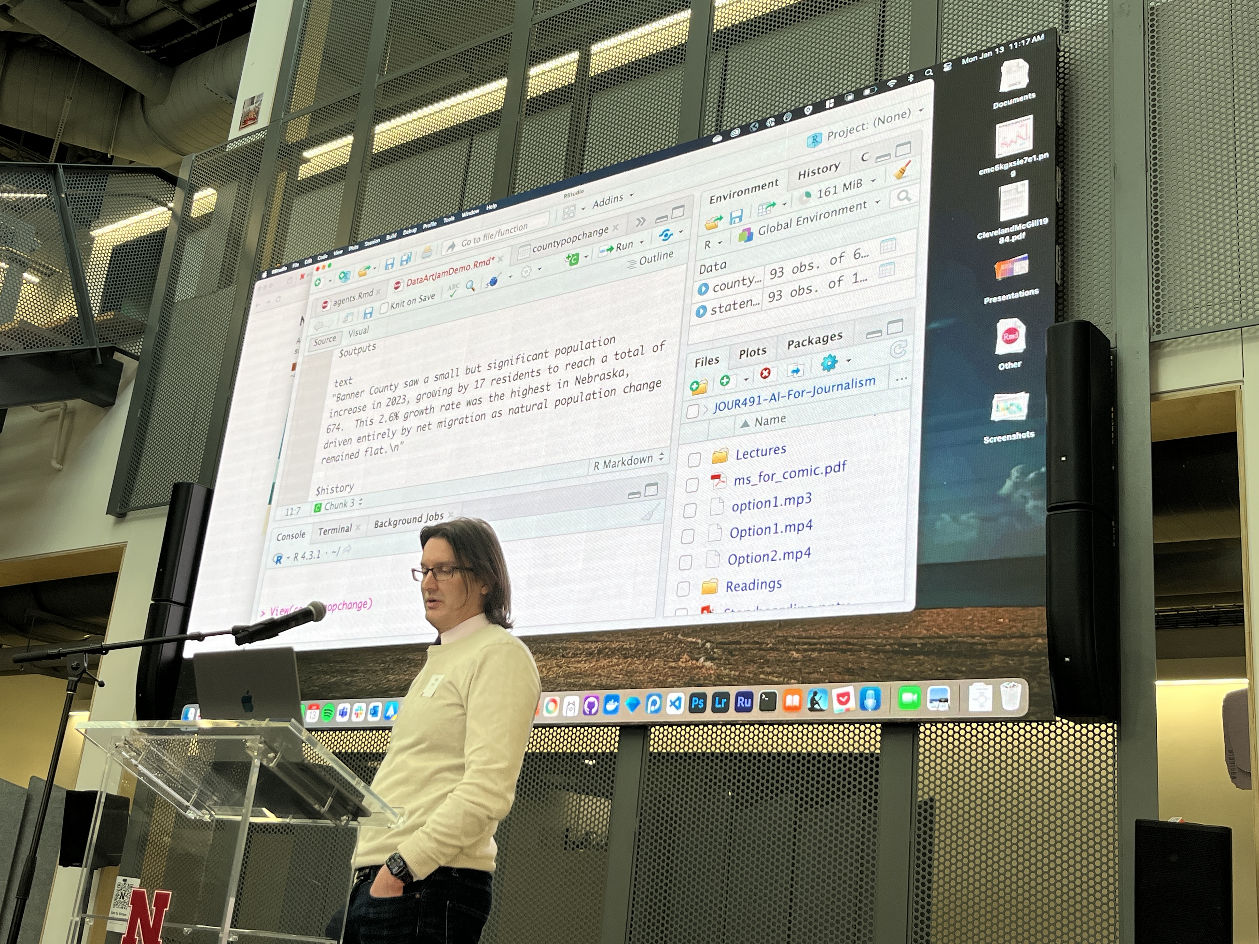 photo of Prof. Waite speaking on stage with slide behind showing a some data journalism AI experiments