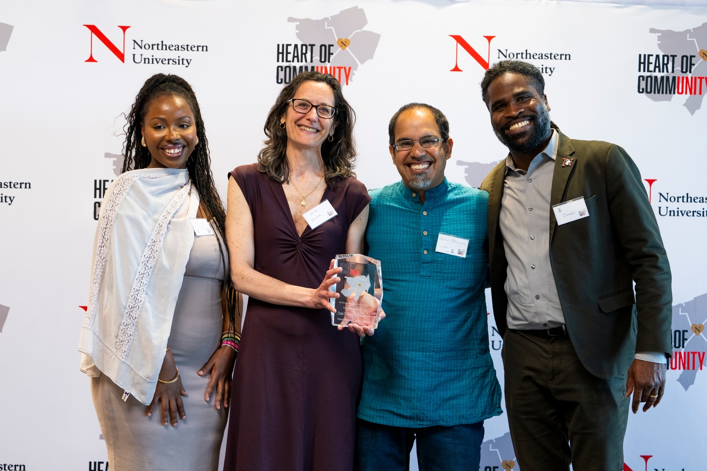 four people standing, one holding an engraved award plaque