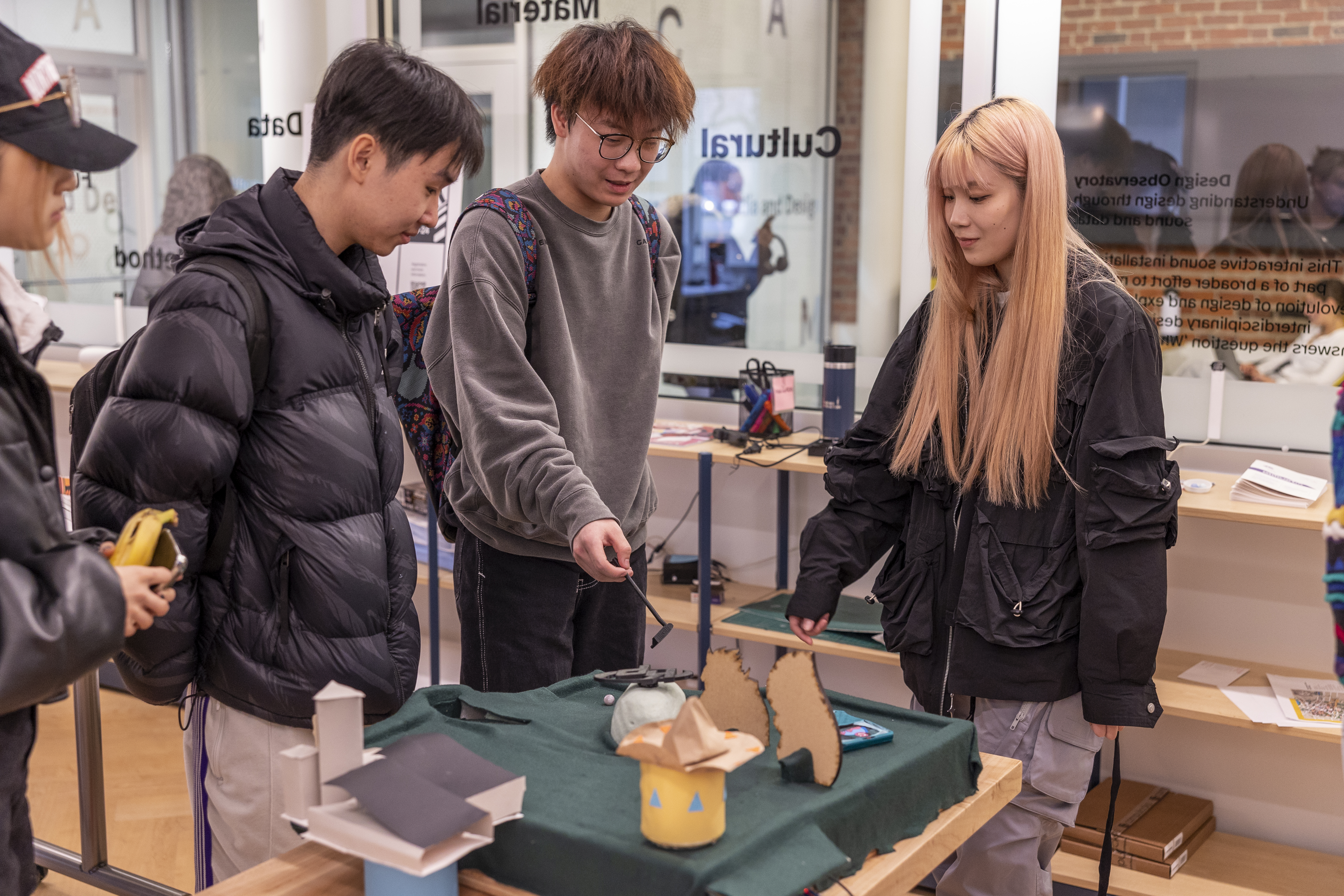 students standing and chatting around a table with the Kim Possible themed mini-mini golf hole on it