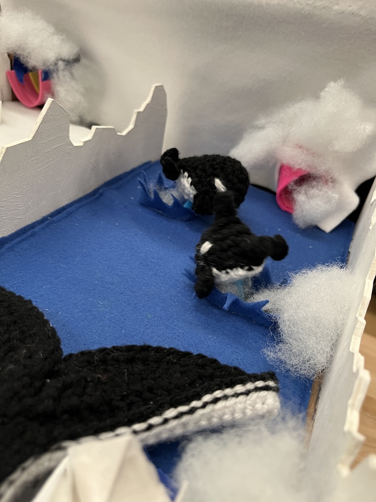 closeup of crocheted whales jumping to stop marble