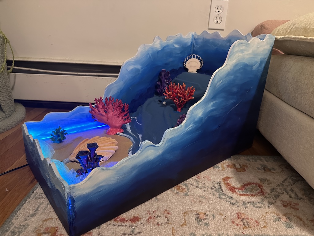 top view of mini mini golf hole colored blue, with a clam and a shark obstacle