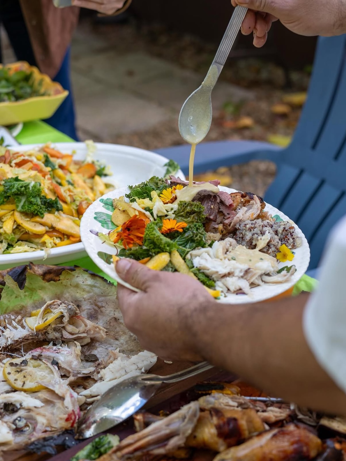 A close-up of Chef Carlos Asseph's hands plating a dish with edible flowers garnished on top.